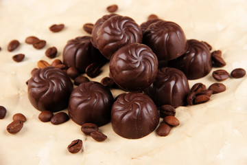 Chocolate candies and coffee beans, on beige paper background