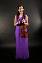 Obraz premium Young female musician in elegant purple gown holding violin and bow, classical music performance and artistic talent, violinist