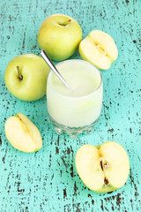 Delicious yogurt in glass with apple on wooden table close-up