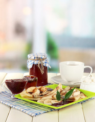 Pancakes with banana on plate on room background