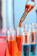 Laboratory pipette with drop of color liquid over glass test