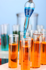 Laboratory pipette with drop of color liquid over glass test