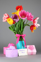 Beautiful tulips in bouquet with gifts and note