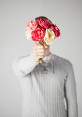 man covering his face with bouquet of flowers