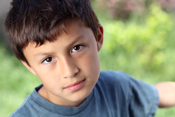 Obraz premium Serious young boy outside with copy space to right
