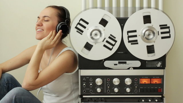 Girl listening to music from retro audio tape recorder