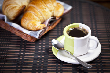 A cup of coffee with croissant basket