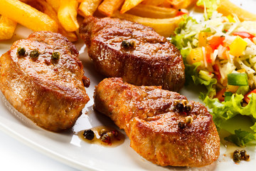 Grilled steaks, French fries and vegetables