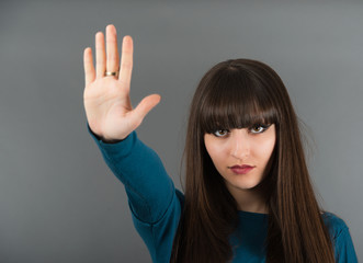 Attractive young woman in a blue blouse. Woman showing a stop si