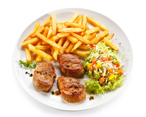 Grilled steaks, French fries and vegetables
