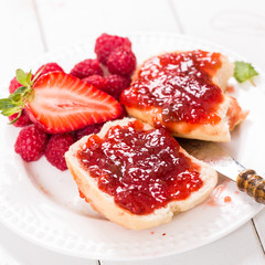 Erdbeer-Himbeermarmelade auf einem Brötchen