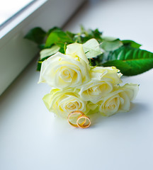 Bouquet of white roses and wedding rings