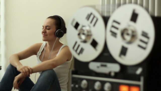 Girl in headphones listening to music from retro tape recorder