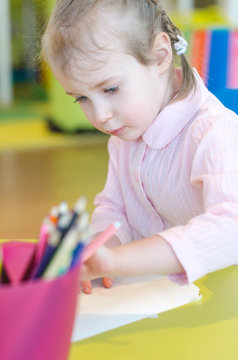 Little girl is drawing with pen in preschool