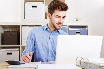 Junger Geschäftsmann arbeitet am Laptop im Büro