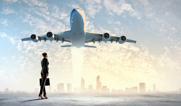 Business woman looking at airplane in sky