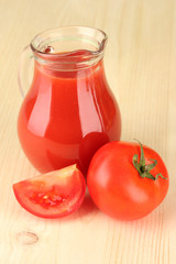 Full jug of tomato juice, on wooden background