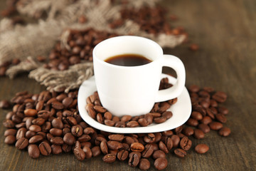 Cup of coffee and coffee beans on wooden background