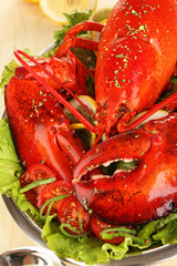 Red lobster on platter with vegetables on wooden table close-up