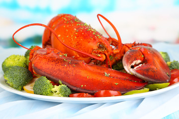 Red lobster on platter with vegetables on table close-up