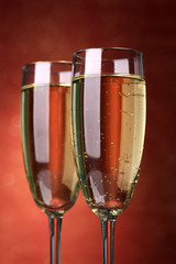 Two glasses of champagne on bright background with lights