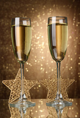 Two glasses of champagne on bright background with lights