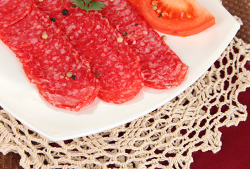 Tasty salami on plate on  napkin close-up