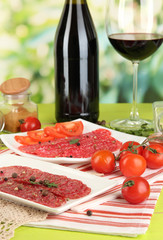 Tasty salami on plates on wooden table on natural background