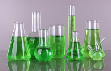 Test-tubes with green liquid on gray background