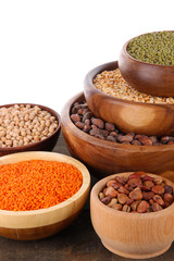 Different kinds of beans in bowls on table isolated on white
