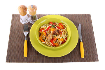 Noodles with vegetables on plate on wooden mat isolated on