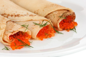 Delicious pancakes with red caviar on plate close-up