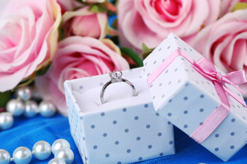 Rose and engagement ring on blue cloth