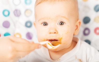 Mom feeds funny baby from  spoon