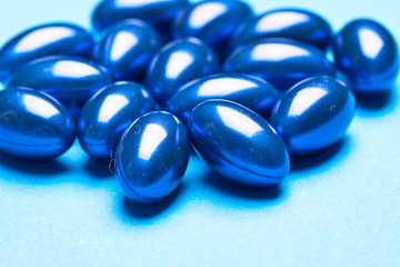 blue vitamin gel capsules isolated on pastel background 