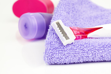 Closeup of pink shaving blade on towel with moisturizer.
