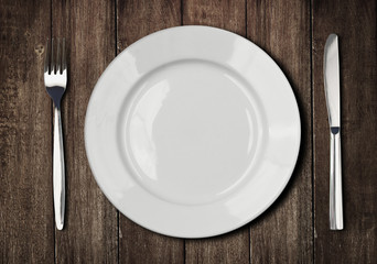 white plate, knife and fork on old wooden table
