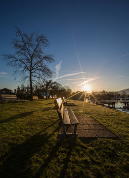 Bench And Sunrise At A Lake Geneva Shore Park.