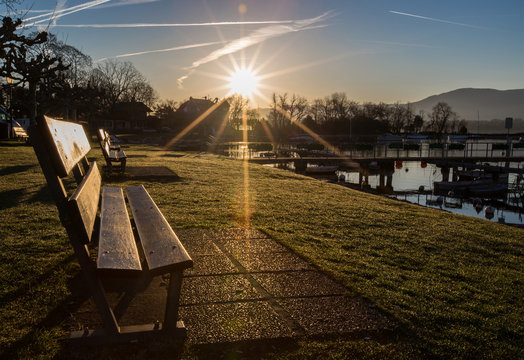 Fototapeta Bench and sunrise at a Lake Geneva shore park.