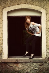 Beautiful redhead in shirt and leggings in the window