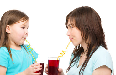 Mother and her daughter are drinking juice