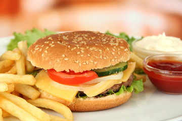 Tasty cheeseburger with fried potatoes, on bright background