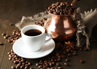Cup of coffee and pot on wooden background