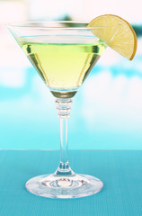 Green cocktail with lime on table on bright background