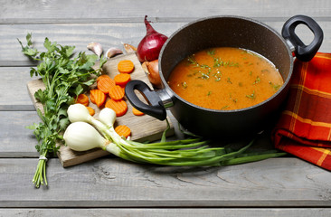Top view on pot of tomato soup and fresh vegetables on old woode