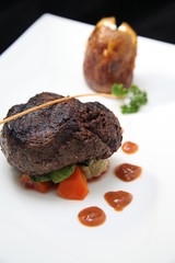 Tenderloin steak portion with potato on black background
