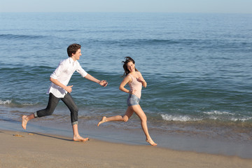 Couple playing and running on the beach