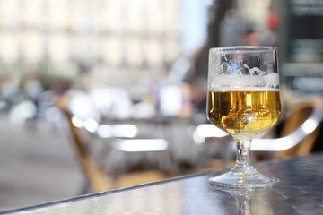Half-finished glass of beer stands on gray windowsill.