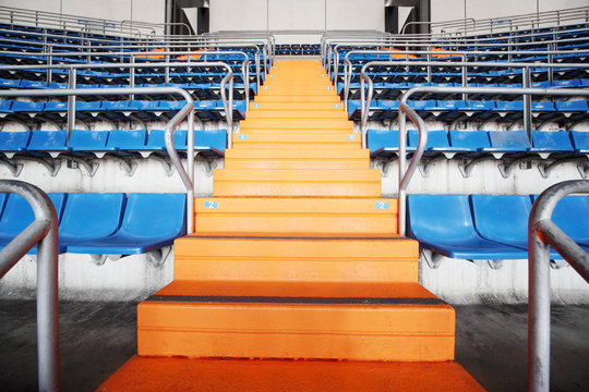 Orange ladder and blue grandstand at large football stadium.