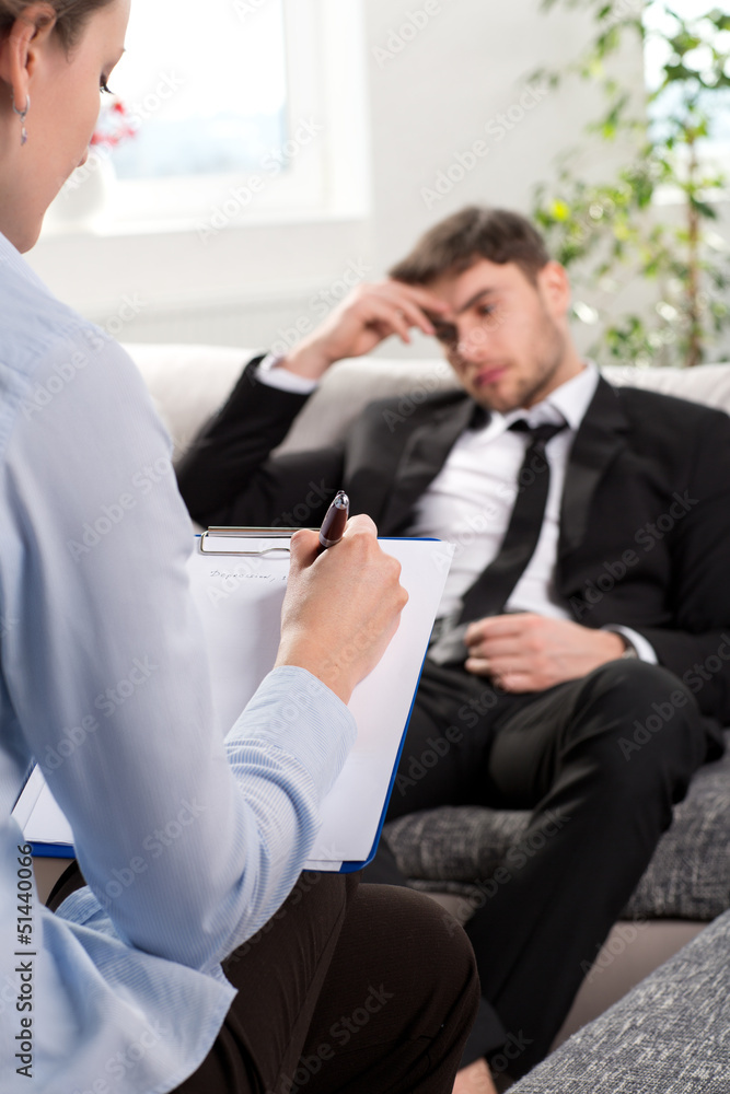 Wall mural Oppressed man talking with psychologist